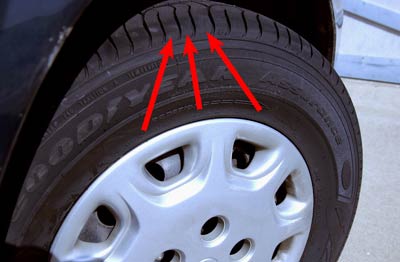 This is one of the 195/70R14s on the Camry. Look close at the arrows which show the varied pitch sequence of the tread blocks. Each of those three blocks is a different length. That reduces annoying tire noise.